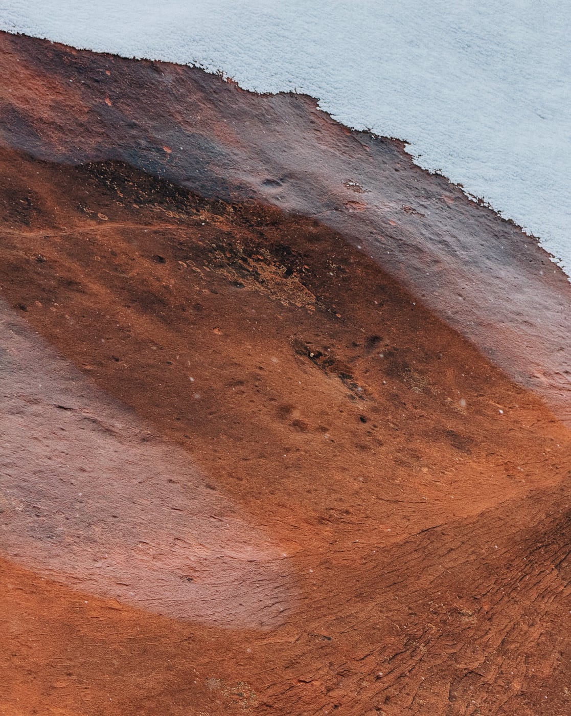 Close-up of a snow-covered red rock sandstone formation with contrasting textures and colors.