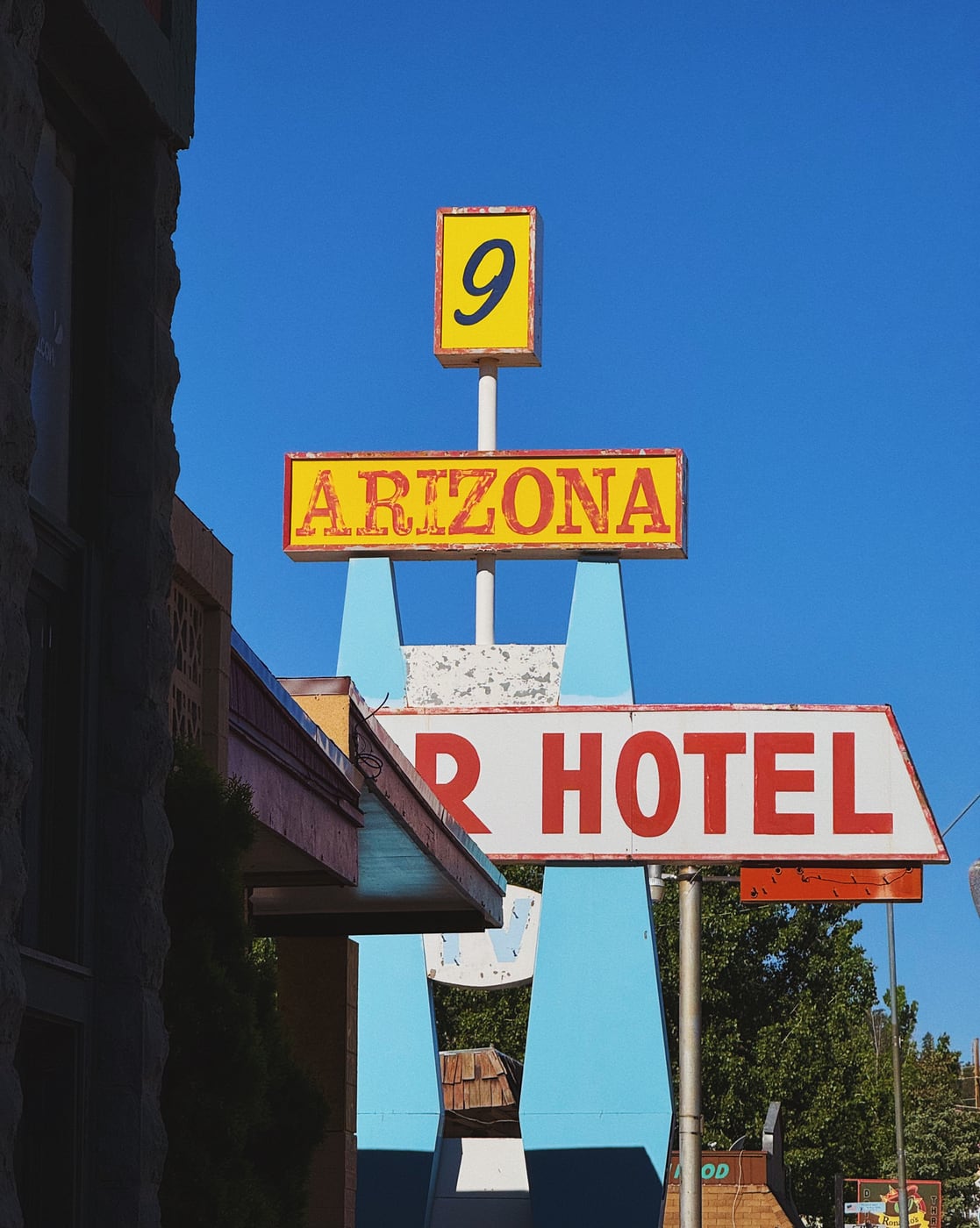 Vintage hotel sign with ‘Arizona’ and the number ‘9’ against a clear blue sky.