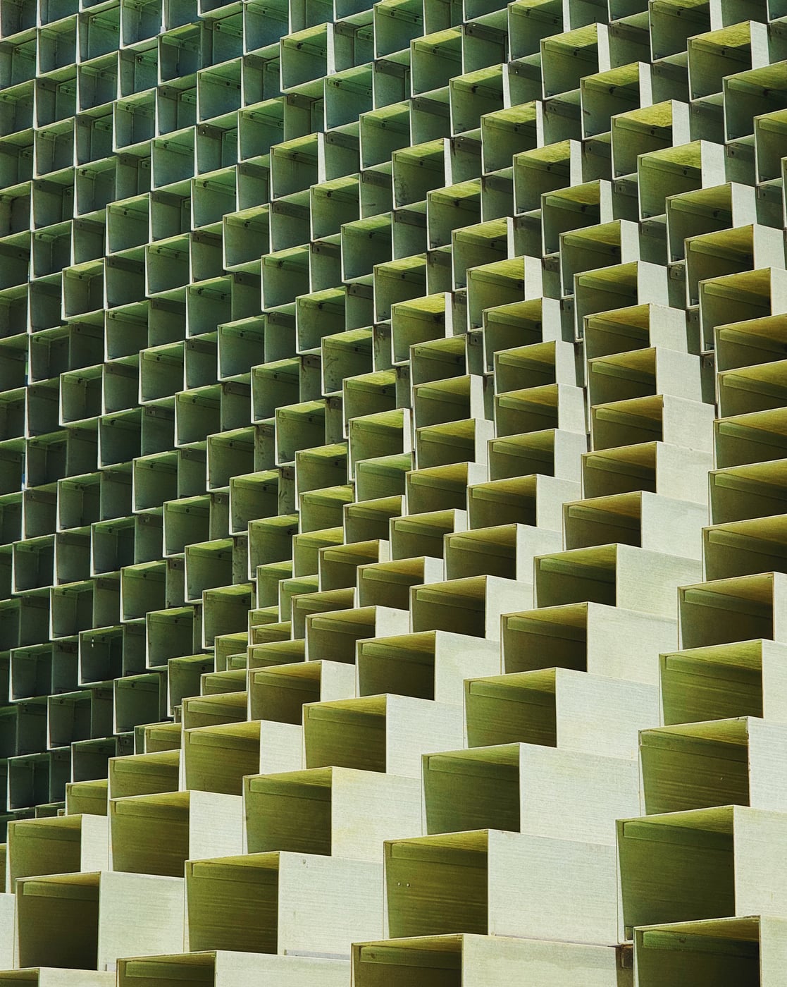 A large public art, metal sculpture. It forms an abstract pattern of greenish square-shaped structures arranged in a stacked grid formation.