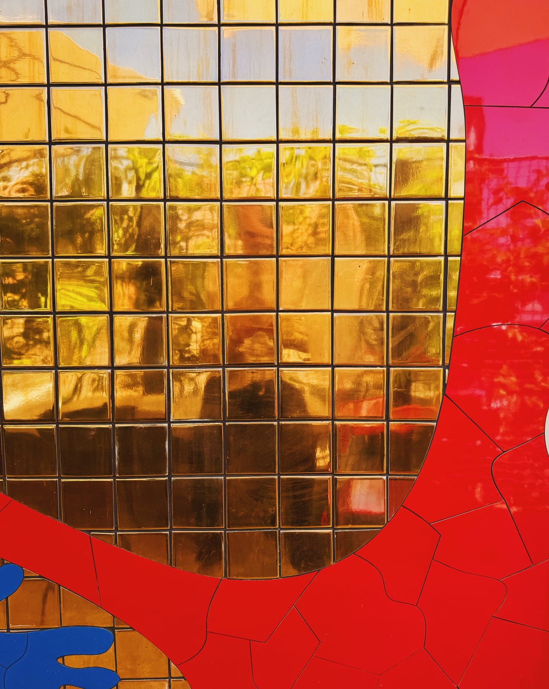 Close-up of a mosaic with reflective gold tiles bordered by red and blue sections.